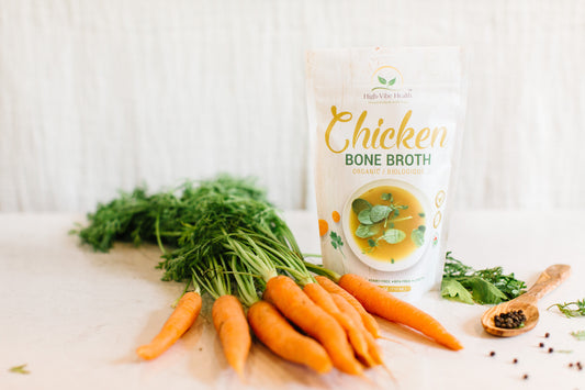Packaged organic chicken bone broth with ingredients like carrots, celery, and herbs displayed in the foreground.